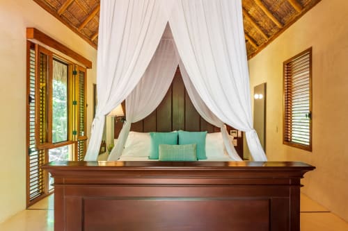 Cama con dosel de lujo con almohadas turquesas en villa Hacienda Chekul del complejo frente al mar en Tulum
