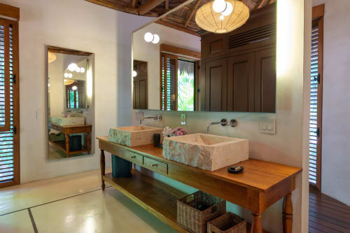 Baño moderno con dos lavabos de piedra y tocador de madera en la villa Hacienda Chekul, Tulum