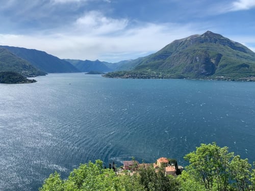 Vista sul lungomare di Como da Varenna con montagne, ville tradizionali e acque turchesi