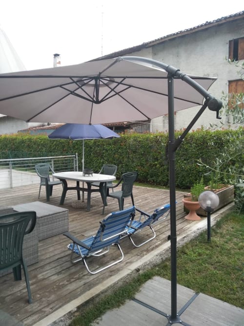 Outdoor garden patio at Casa Meravigliosa with cantilever umbrella, dining table, loungers, and hedge privacy