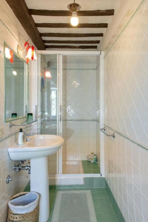 Bagno moderno nella Suite Rosella di Villa Pandolfi Elmi a Spello con doccia in vetro, lavabo a colonna e piastrelle verdi