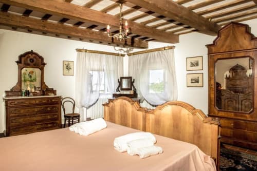 Camera Rosella Suite a Villa Pandolfi Elmi a Spello con soffitto in travi di legno, mobili antichi e viste panoramiche