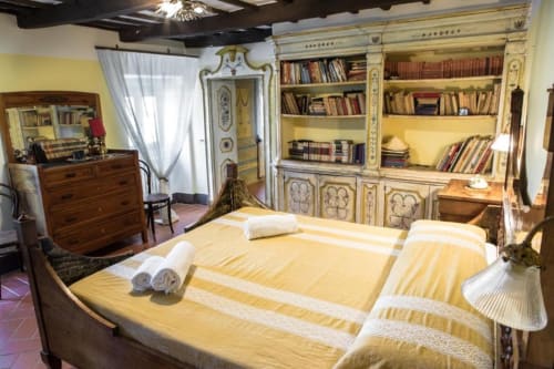 Camera Catherine Suite a Villa Pandolfi Elmi a Spello con biancheria gialla, arredi antichi e librerie