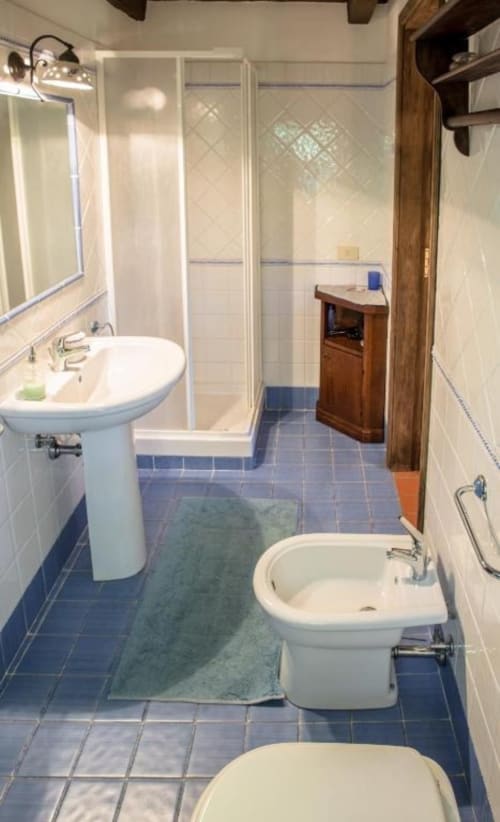 Bagno della Catherine Suite a Villa Pandolfi Elmi, Spello con doccia, lavabo su colonna, bidet e pavimento in piastrelle blu