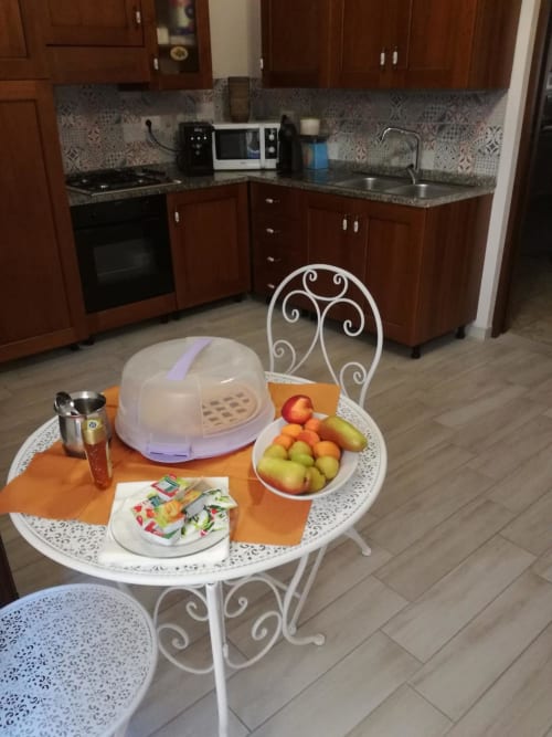 Zona pranzo della cucina moderna di Zia Amalia Villa ad Alghero con tavolo bianco, frutta fresca e dettagli decorativi