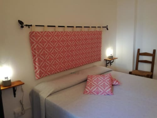 Camera da letto di Zia Amalia Villa Asfodelo ad Alghero con testata rossa decorata, biancheria bianca e arredi in legno.
