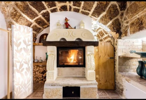 Rustic stone fireplace with cream-colored decorative surround in CorteLirice Paradiso's Sottano 1 apartment, featuring