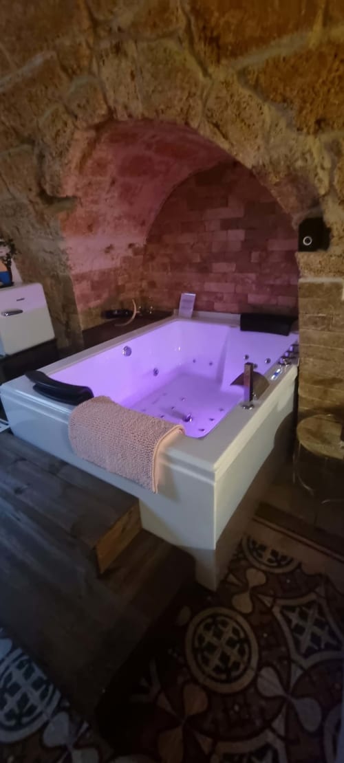 Luxurious Jacuzzi tub with purple lighting in stone-walled apartment at CorteLirice Paradiso, Italy