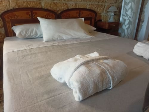 CorteLirice Paradiso bedroom with rolled towels on bed, wooden headboard, and white pillows in Sottano 1 apartment