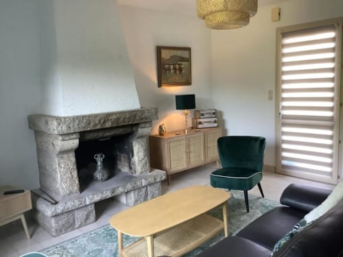 Salon chaleureux du gîte Le Village Du Moulin à Sizun avec cheminée en pierre, mobilier moderne et lumière naturelle