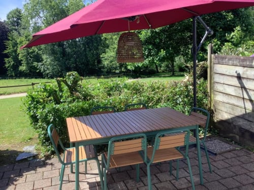 Parasol rouge en porte-à-faux surplombant la table à manger de la maison d'hôtes Le Village Du Moulin à Sizun, France