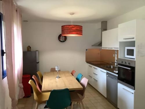 Cuisine-salle à manger moderne du gîte Le Village Du Moulin à Sizun avec chaises colorées et luminaire suspendu rouge