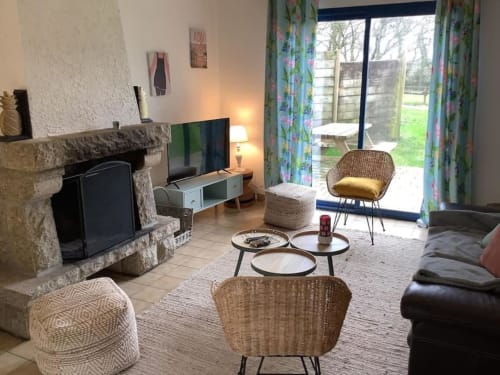 Séjour douillet au Village Du Moulin à Sizun avec cheminée, télévision et vue sur le jardin par les portes vitrées