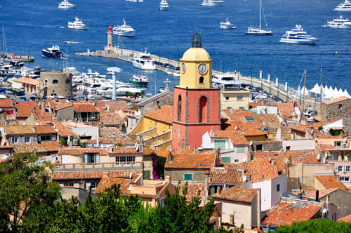 Colorful seaside village of La Croix Valmer with red-roofed buildings, yellow bell tower, harbor boats, and Mediterranean Sea