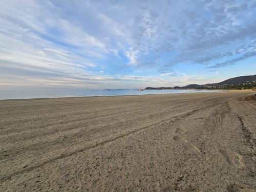 Serene sandy beach at Villa Sigahi in La Croix Valmer, France, with sailboats and coastal hills