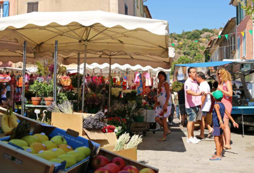 Marché local à La Croix Valmer près de Villa Sigahi avec parasols, produits frais et clients par beau temps