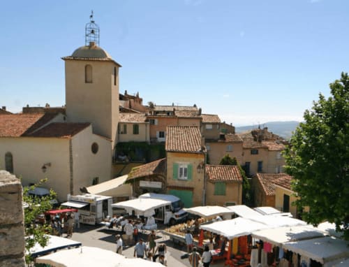 Cour du gîte Villa Sigahi avec tour d'église médiévale, toits en terre cuite et étals du marché à La Croix Valmer