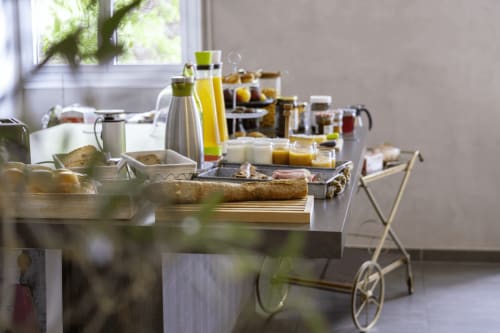 Buffet de petit-déjeuner à La Maison D'olivier avec pâtisseries, jus, pain et confitures près d'une fenêtre ensoleillée