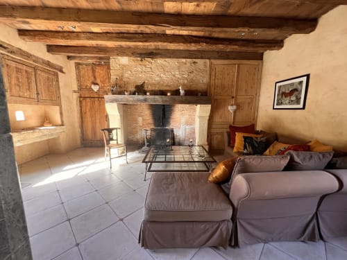 Salon rustique du Lapin sur le Toit avec cheminée en pierre, poutres apparentes et coin détente confortable