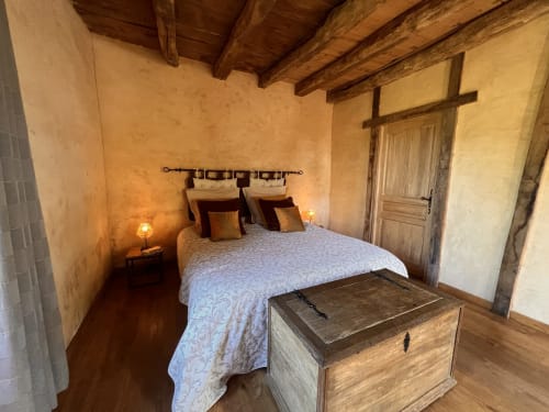 Chambre rustique à la gîte Le Lapin sur le Toit, Rouffignac, avec poutres apparentes, murs en terre cuite et mobilier d'époque