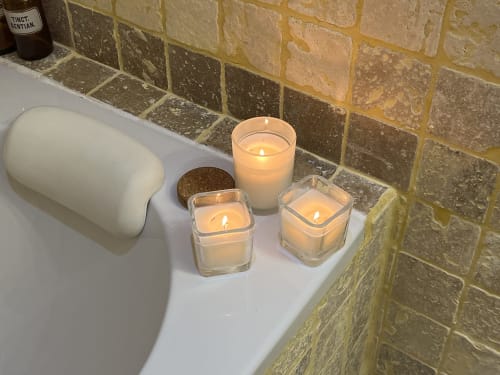 Bougies allumées et papier toilette sur l'étagère de la salle de bain du gîte Le Lapin sur le Toit à Rouffignac, France