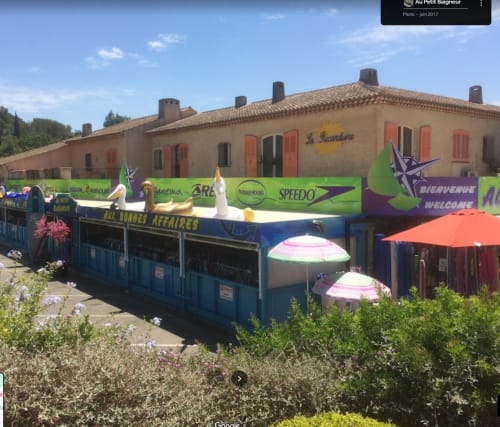 Villa Sigahi Gîte à La Croix Valmer avec étals colorés du marché et parasols devant un charmant bâtiment en pierre