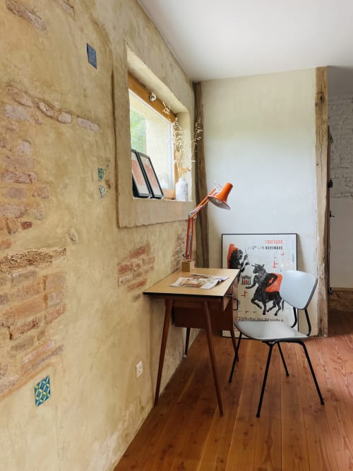 Espace de travail rustique à la villa Montaut avec mur de briques apparentes, bureau en bois, lampe orange moderne et chaise vintage