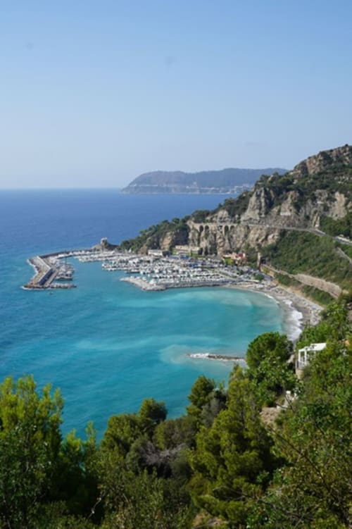 Aerial view of Hotel Beau Rivage's marina and beach in Alassio, Italy with turquoise waters and coastal cliffs