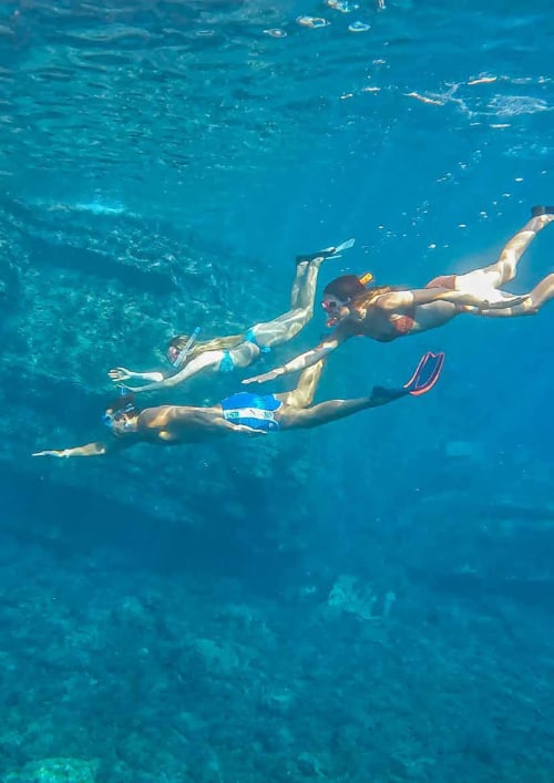 Four snorkelers swimming together in crystal clear turquoise water at Hotel Beau Rivage, Alassio Italy