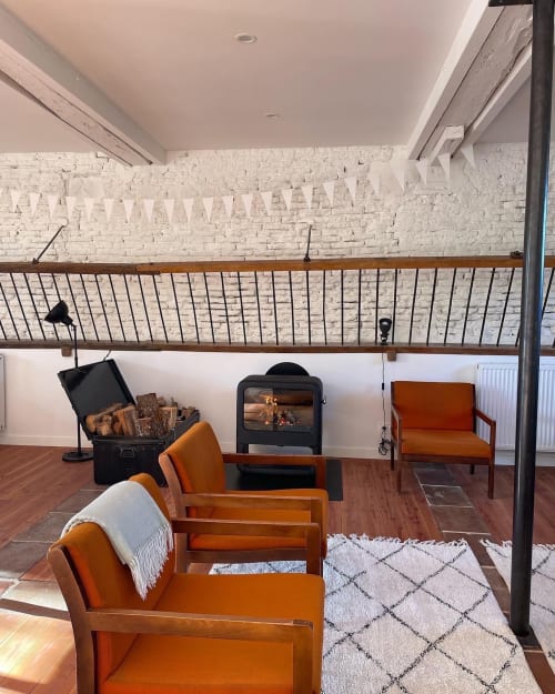 Cozy loft lounge at Maison Monsieur Léger with fireplace, orange chairs, white brick walls, and wooden beams in Montaut