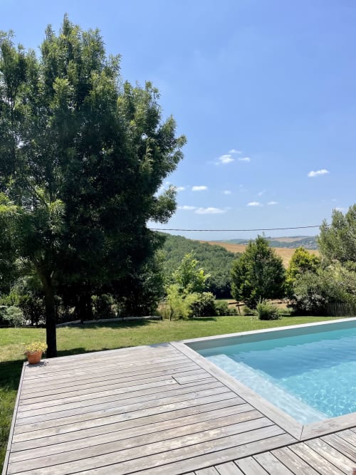 Wooden deck with swimming pool overlooking lush green countryside at Maison Monsieur Léger, Montaut