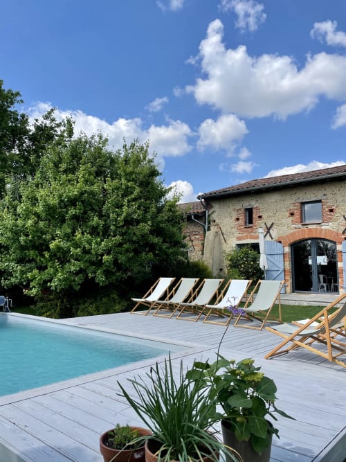 Luxury pool deck at Maison Monsieur Léger with lounge chairs, stone villa, and manicured gardens in Montaut, France