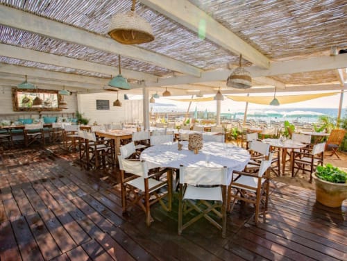 Terrasse sur le toit de la Villa Sigahi à La Croix Valmer avec tables rondes, chaises en bois et vue sur la mer côtière