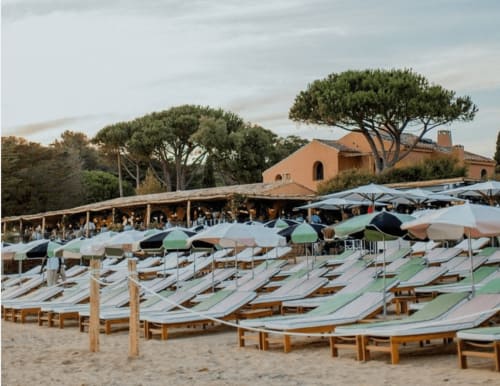 Club de plage de la Villa Sigahi à La Croix Valmer avec transats en bois, parasols bleus et architecture méditerranéenne.