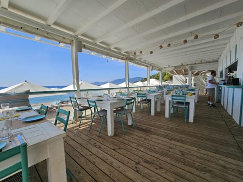 Terrasse de salle à manger en bord de mer de la Villa Sigahi avec pergola blanche, chaises turquoise et vue sur la mer Méditerranée à La Croix Valmer