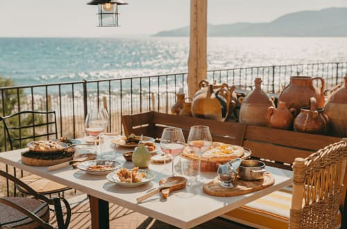 Table de déjeuner en bord de mer à la Villa Sigahi à La Croix Valmer, avec vin, pâtisseries et vue sur la Méditerranée