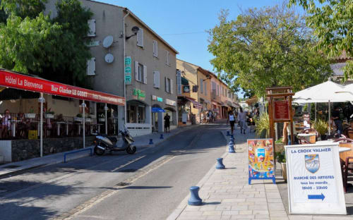 Charming village street in La Croix Valmer with hotel, shops and market stalls under sunny skies
