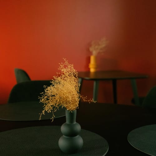 Fleurs dorées séchées dans un vase vert à La Guirtelle B&B à Lainsecq, France, avec éclairage ambiant rouge
