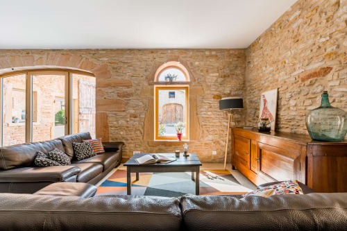 Salon avec murs en pierres dorées et canapés en cuir, maison de pagneux, chambres d'hôtes en Beaujolais des Pierres dorées