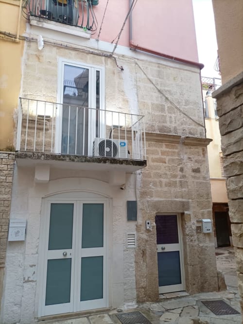 Facciata dell'hotel Newhouse a Bari con esterno in pietra, porte bianche, balcone con unità di climatizzazione e accesso alla vista della città