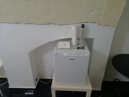 White dryer and washing machine setup in Newhouse Bari hotel room with cream brick wall