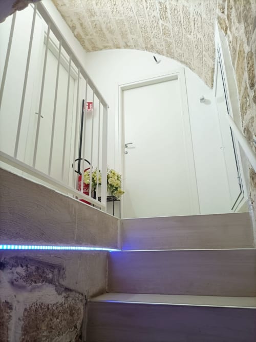 Modern stairwell at Newhouse hotel in Bari with white doors, blue LED lighting, and potted flowers