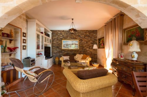 Elegante soggiorno della Villa Margherita a Santeramo in Colle con camino in mattoni, poltrone comode e arredamento rustico