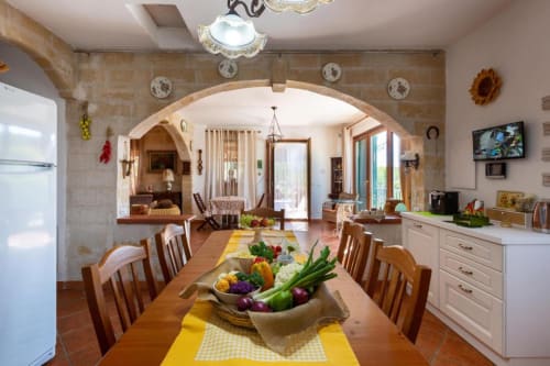 Cucina attrezzata e zona pranzo di Villa Margherita con verdure fresche, tavolo in legno e arco che si apre sulla zona living