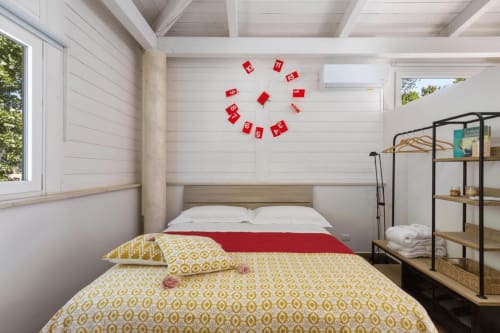 Camera da letto moderna e luminosa a Villa Margherita con biancheria gialla decorata, stendardo rosso, travi in legno e ampie