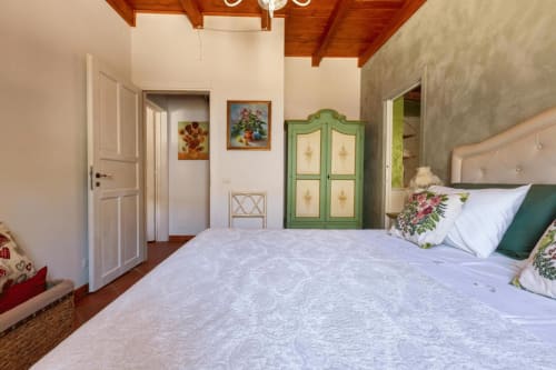 Camera spaziosa a Villa Margherita a Santeramo in Colle con guardaroba verde, opere floreali, travi in legno