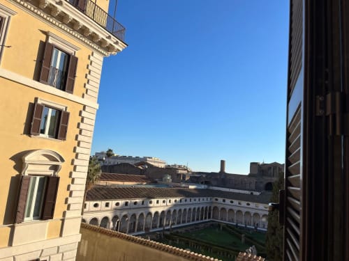 Suite Michelangelo Roma: vista panoramica su cortile storico romano con archi e prato verde, edificio rinascimentale giallo