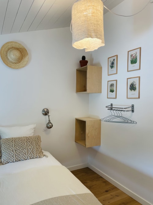 Chambre cosy de la Maison Monsieur Léger avec lit, étagères murales en bois, art botanique et lampadaire