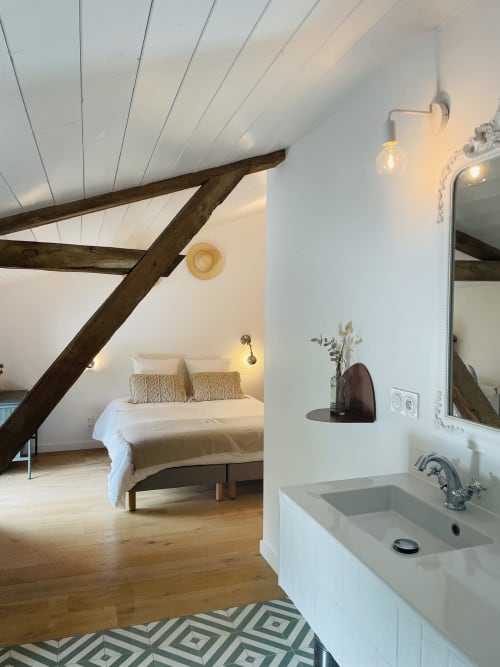 Chambre loft à la Maison Monsieur Léger : poutres apparentes, murs blancs, parquet et salle d'eau attenante