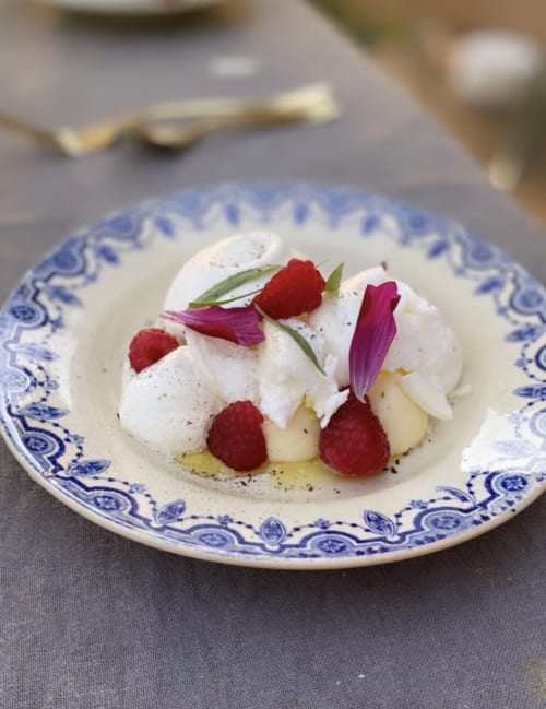 Elegant plated dessert with whipped cream, raspberries, and edible flowers at Maison Monsieur Léger, Montaut